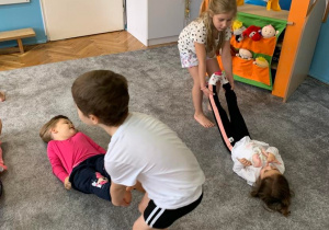 Zajęcia w grupie 1. Dzieci w parach. Jedno leży na podłodze, a drugie ciągnie za nogi.